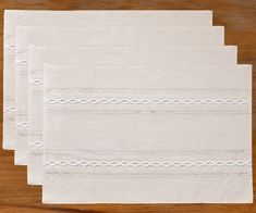 three white placemats sitting on top of a wooden table