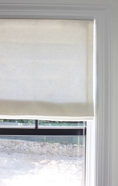 a window with a white roman blind in front of it