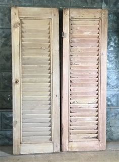 two wooden doors with shutters in front of a brick wall and concrete flooring