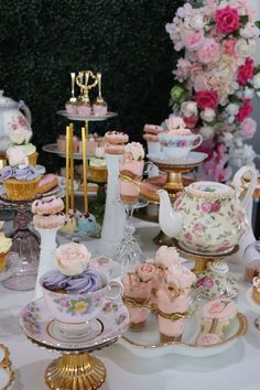 a table topped with lots of different types of cupcakes and teapots