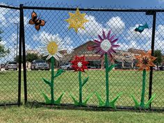 colorful paper flowers are on display behind a chain link fence