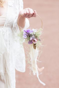 a woman is holding a flower arrangement in her hand while wearing a white lace dress