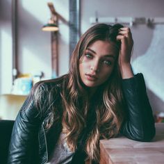 a woman sitting at a table with her hand on her head and looking off to the side