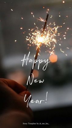 someone holding a sparkler with the words happy new year written on it in white