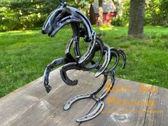 a horse head made out of horseshoes sitting on top of a wooden table in the grass