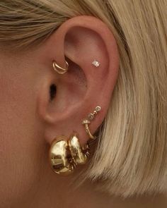 a woman with blonde hair wearing gold ear piercings and an earring on her left ear