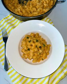 a white plate topped with macaroni and cheese next to a pot of pasta