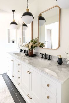 a bathroom with two sinks, mirrors and lights on the wall above them is shown