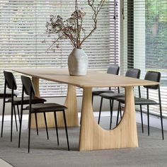 a dining room table with chairs and a vase on it