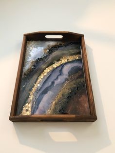 a wooden tray with an abstract painting on the front and sides in gold, black, and white