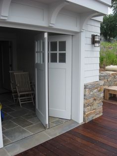 an open door to a white shed with wooden decking and chairs in the background