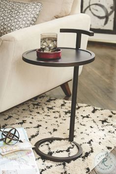 a living room with a white couch and black table on top of the rug in front of it