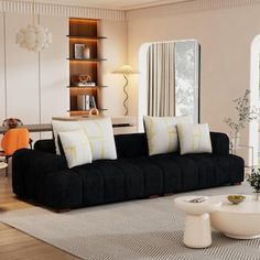 a living room filled with black couches and white pillows on top of a rug