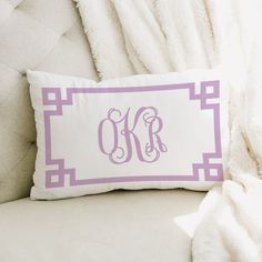 the monogrammed pillow is on top of a white chair with a blanket behind it