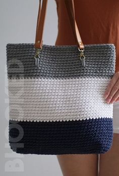 a woman is holding a purse made out of knitted material and leather handles, with her hand on the shoulder