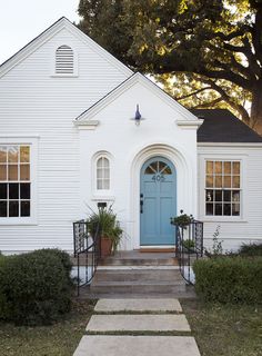 a white house with a blue door and steps leading up to the front entrance area