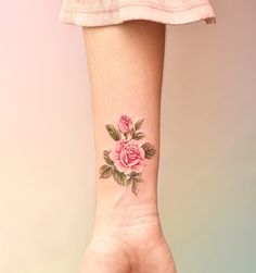 a woman's hand with a pink rose tattoo on her left wrist and right arm