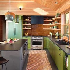 a kitchen with green cabinets and an area rug in front of the stove top oven