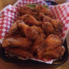 chicken wings and green beans in a basket on a wooden table with red checkered napkins