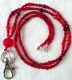 Red Beaded Lanyard This Red Beaded Lanyard can be used as a badge holder, an I.D. holder, keychain necklace, watch holder - it's a multi-use accessory for home or office! 34" in length, long enough to put on or remove overhead. It also has an easy-to-use metal lobster clasp for your convenience. It's made with red glass beads and strung on strong C-Lon beading cord. Snap-on badge holder, clip, and keyring are included to keep your badges or keys ready when you need them. This Red Beaded Lanyard Red Lanyards With Key Leash, Adjustable Red Lanyard With Key Leash, Adjustable Red Lanyard As Gift, Red Lanyard With Key Leash As Gift, Red Lanyards With Key Leash For Gifts, Keychain Necklace, Beaded Lanyard, Beading Cord, Watch Holder