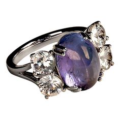 Gorgeous dinner featuring a clean sparkling blue-purply oval Tanzanite cabochon enhanced by two pairs of glittering colorless genuine Zircons.  This stunning flashing ring will delight wherever it goes. The hand made setting is 14K white gold four prong with split shank.First discovered in Tanzania (hence its name) in 1967, Tanzanite was chosen as the December birthstone by the American Gem Trade Association in 2002. Its discovery marked a momentous occasion in the world of gemstones and the gem Flash Ring, Maasai People, Dinner Ring, Turn Blue, Maasai, Blue Gems, Split Shank, December Birthstone, Cocktail Rings