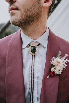 a man wearing a red suit and flower boutonniere with a white flower in his lapel