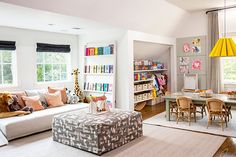 a living room filled with furniture and bookshelves next to a dining room table