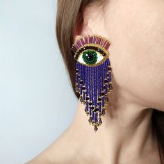 a close up of a woman's face wearing earrings with an eye on it