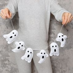 a young child is holding two white ghost garlands