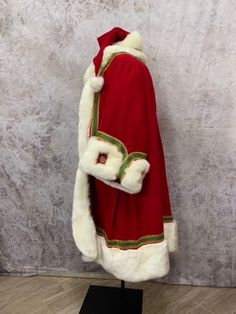 a red cape with white fur on top and gold trim around the collar, sitting on a black stand