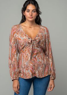 A sweet tie-front top designed in a vintage-inspired paisley print. Paisley print Relaxed fit Long voluminous sleeve Elastic wrist cuff Plunging v-neckline Button front Tie front detail Half elastic waist in back Bohemian top A bohemian paisley print adds a retro touch to this classic blouse. Featuring voluminous long sleeves, a button front, and a flirty v-neckline with a tie front detail. An effortless style for summer or fall, we love to pair it with vintage denim. Model is 5'8, wearing a siz Fall Paisley Print V-neck Blouse, Fall V-neck Blouse With Paisley Print, Feminine V-neck Blouse With Tie Sleeves, Chic V-neck Tops With Paisley Print, Feminine V-neck Tops With Tie Sleeves, Chic V-neck Paisley Print Tops, Volume Sleeves, Classic Blouse, Bohemian Top