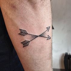 an arrow tattoo on the left arm is shown in black and grey ink, with two arrows