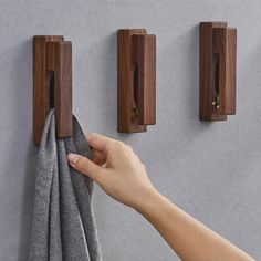 a person is holding a towel in front of two wooden hooks