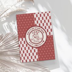 a red and white brochure sitting on top of a table next to palm fronds