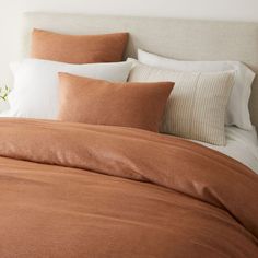 a bed with two pillows on top of it and one pillow in front of the headboard