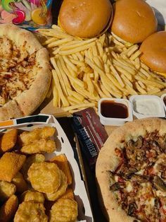 two pizzas and some fries on a table