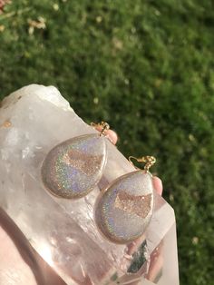 These holographic Teardrop geode earrings made from resin shift from clear gold to a beautiful sparkly rainbow. They are lightweight and won't bother your ears. Please be aware that resin is heat resistant up to 135 degrees. Wearing these earrings in extremely hot temperatures will cause them to be pliable. If this happens, simply place in a cooler location. I am not responsible for any damaged earrings due to extreme heat. Made by Katie Glover Resin Art by Katie 2020 Contact me on my Instagram Hypoallergenic Resin Jewelry For Parties, Sparkling Teardrop Dangle Earrings As Gift, Iridescent Sparkling Jewelry As Gift, Sparkling Iridescent Jewelry For Gifts, Sparkling Dangle Teardrop Earrings Gift, Sparkling Drop Teardrop Earrings As Gift, Sparkling Iridescent Jewelry As Gift, Sparkling Teardrop Crystal Earrings For Gifts, Sparkling Drop Teardrop Earrings