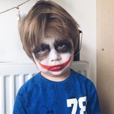 a young boy with his face painted like a clown