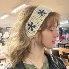 a woman wearing a crocheted headband with blue flowers on the front and side