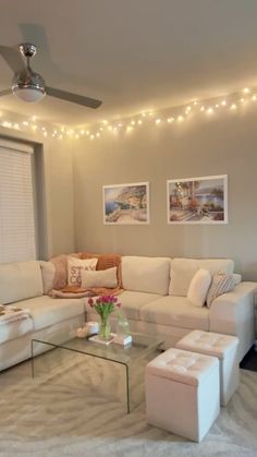 a living room with white furniture and lights on the ceiling above it, along with a glass coffee table