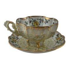 an antique tea cup and saucer with gold trimmings on the rim,