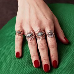 a woman's hand with three rings on her fingers and one ring in the shape of an eye