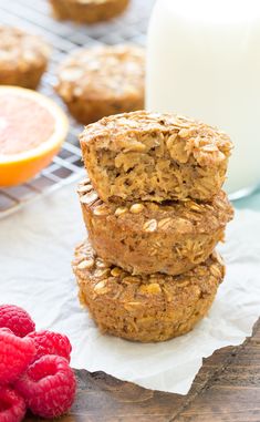 three oatmeal muffins stacked on top of each other next to raspberries