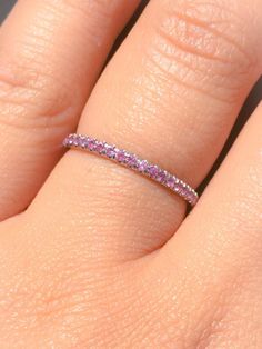 a woman's hand with a pink diamond ring on her left hand and the band is