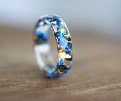 a wedding ring with blue and gold stars on it sitting on a wooden table top