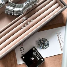 an assortment of jewelry sits in a box on top of a wooden table next to other items