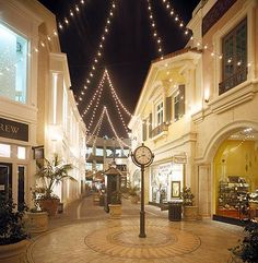 an empty shopping mall with lights strung from the ceiling