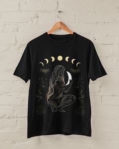 Thanks for stopping by! Grunge Fairycore Moon Phases T-shirt Printed on a super soft, cotton tee Dispatched in 5 working days or sooner Unisex Free UK delivery Material: 100% ringspun cotton. Chest (to fit): S  34/36   M  38   L  40/42   XL  44/46   XXL  48/50 ECO-FRIENDLY Each garment is made to order, reducing extra material and energy that would be otherwise wasted We use DTG printing process which is easier on the environment than screen-printing Our ink is bright and also eco-friendly. Do n Black Fairycore Crew Neck Top, Fairy Grunge Crew Neck T-shirt For Festival, Bohemian Short Sleeve T-shirt With Moon Print, Festival Fairy Grunge Crew Neck Top, Fairy Grunge Shirt, Alt Clothing, Grunge Clothing, Festival Shirt, Grunge Fairycore