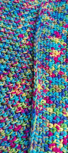 a multicolored crocheted blanket laying on top of a bed