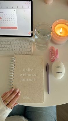 a woman is sitting at a desk with a notebook and candle in front of her